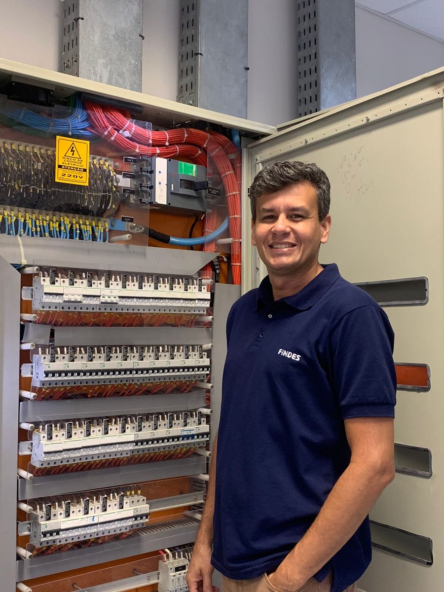 Michael Schiavo, técnico eletricista, ao lado de um quadro de distribuição elétrica